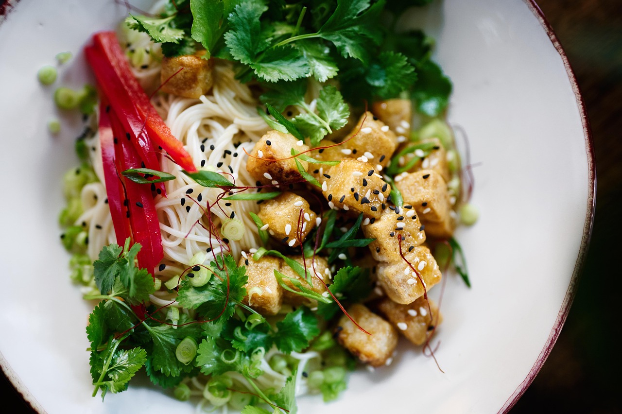 Eine Schüssel mit Essen, Kräuter, Salat, Reisnudeln und Tofu.